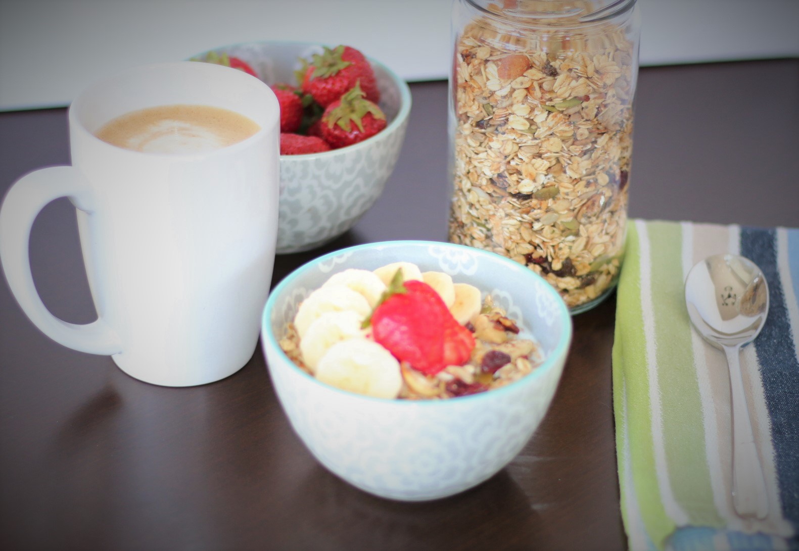 Breakfast scene with toasted muesli, coffee and strawberries.